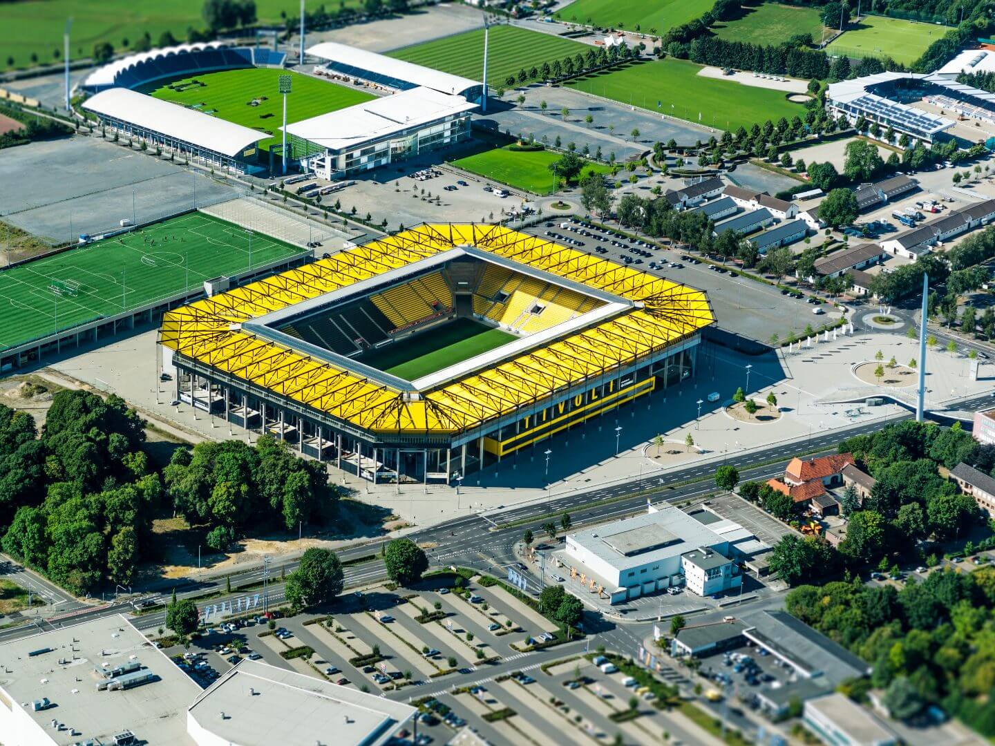 Luftaufnahme des Tivoli Fußballstadions in Aachen mit gelben Tribünen und Spielfeld.