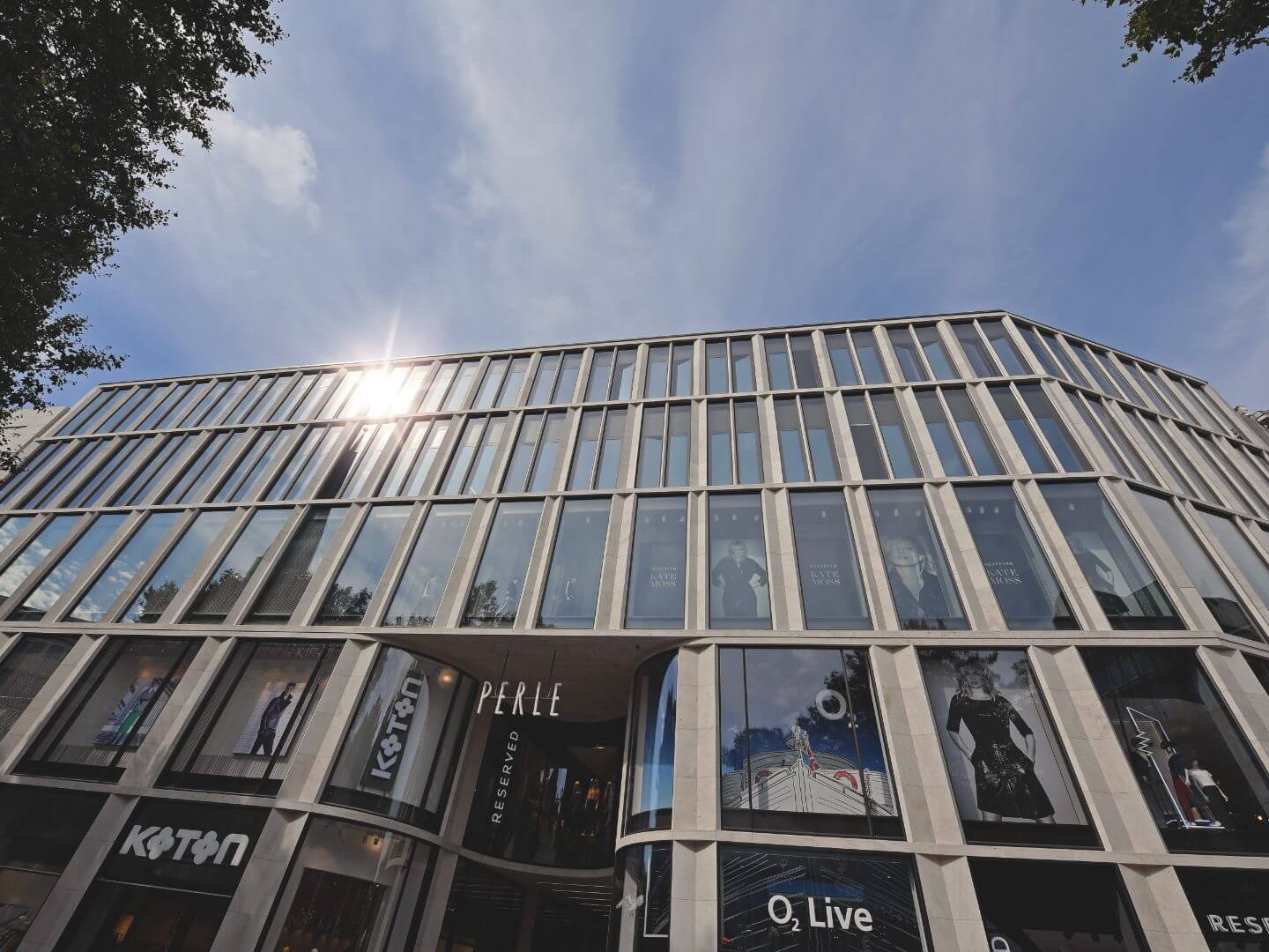Fassade des modernen Büro- und Geschäftshauses in der Spitaler Straße Hamburg, realisiert als Bauprojekt der Hellmich Gruppe, mit großen Fensterfronten und Sonnenreflexion.