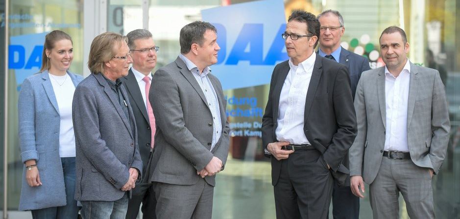 Eine Gruppe von Geschäftspersonen im Gespräch vor einem Bürogebäude in Kamp-Lintfort.