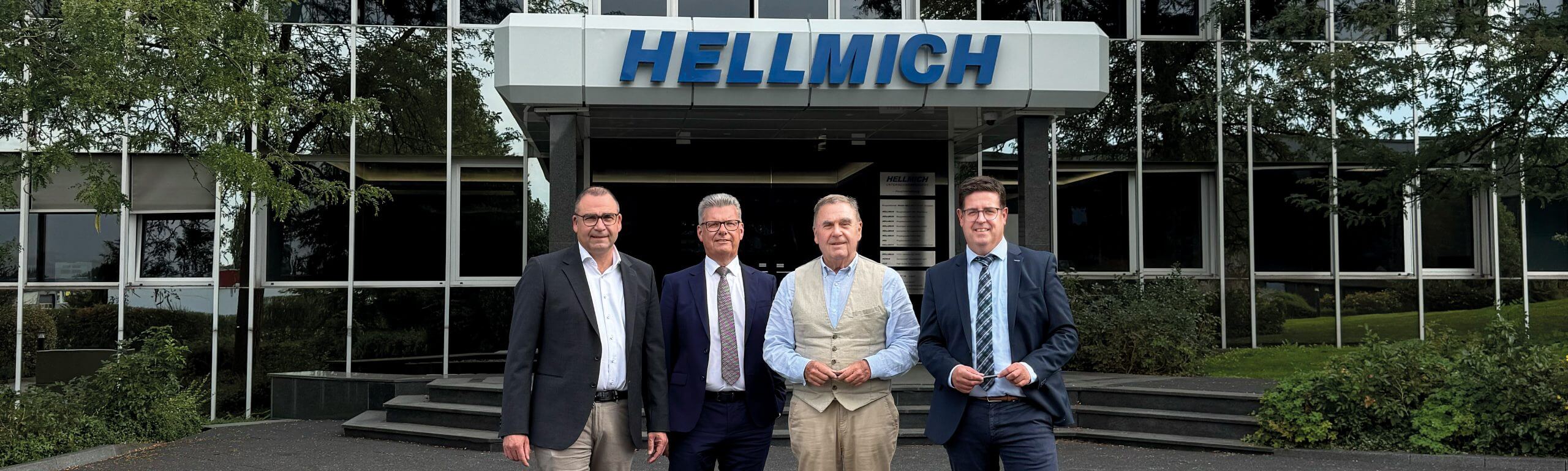 Vier Führungskräfte von HELLMICH gemeinsam vor dem Eingang des Unternehmens.