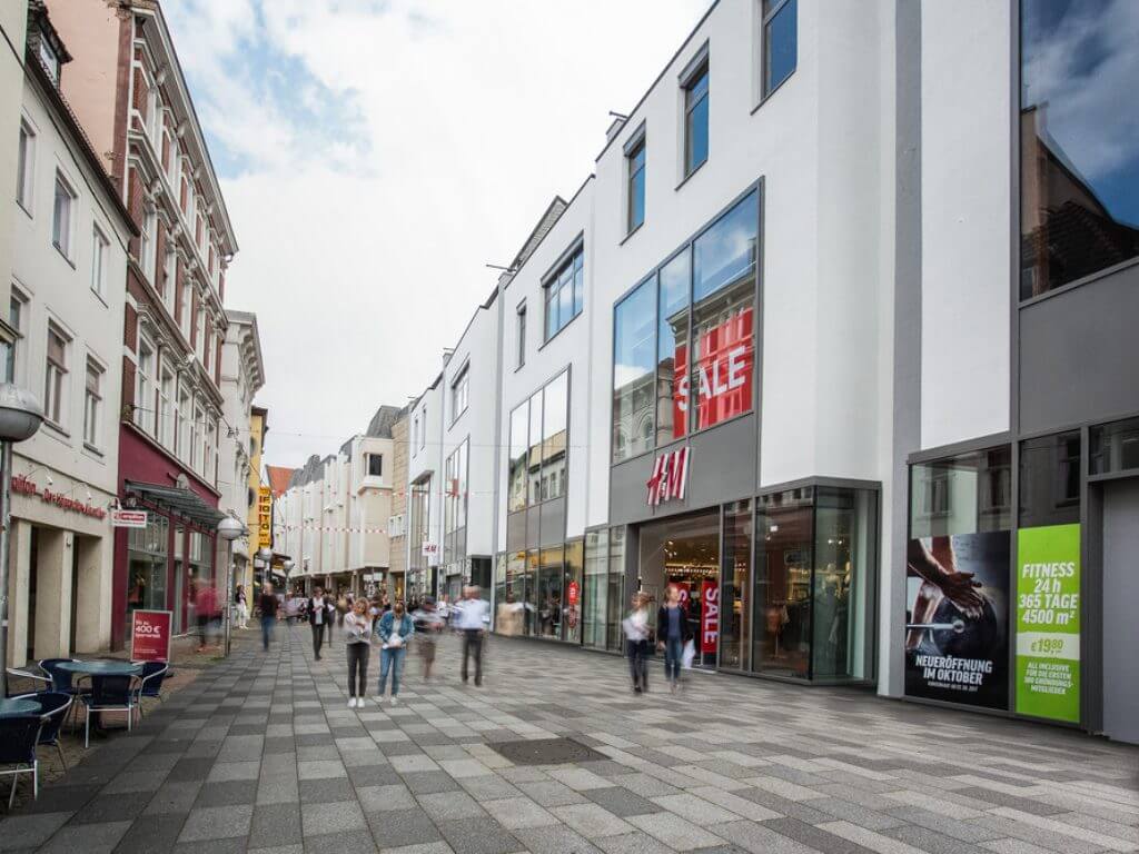 Moderne Einkaufsstraße mit Geschäftshaus Wesertor Minden und beleuchteten Schaufenstern.