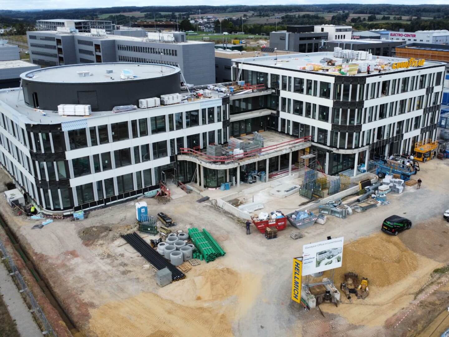 Luftaufnahme der im Bau befindlichen Goodyear Europazentrale, ein modernes Bürogebäude, das von Hellmich realisiert wird, mit Baumaterialien und Befestigungsarbeiten im Vordergrund.