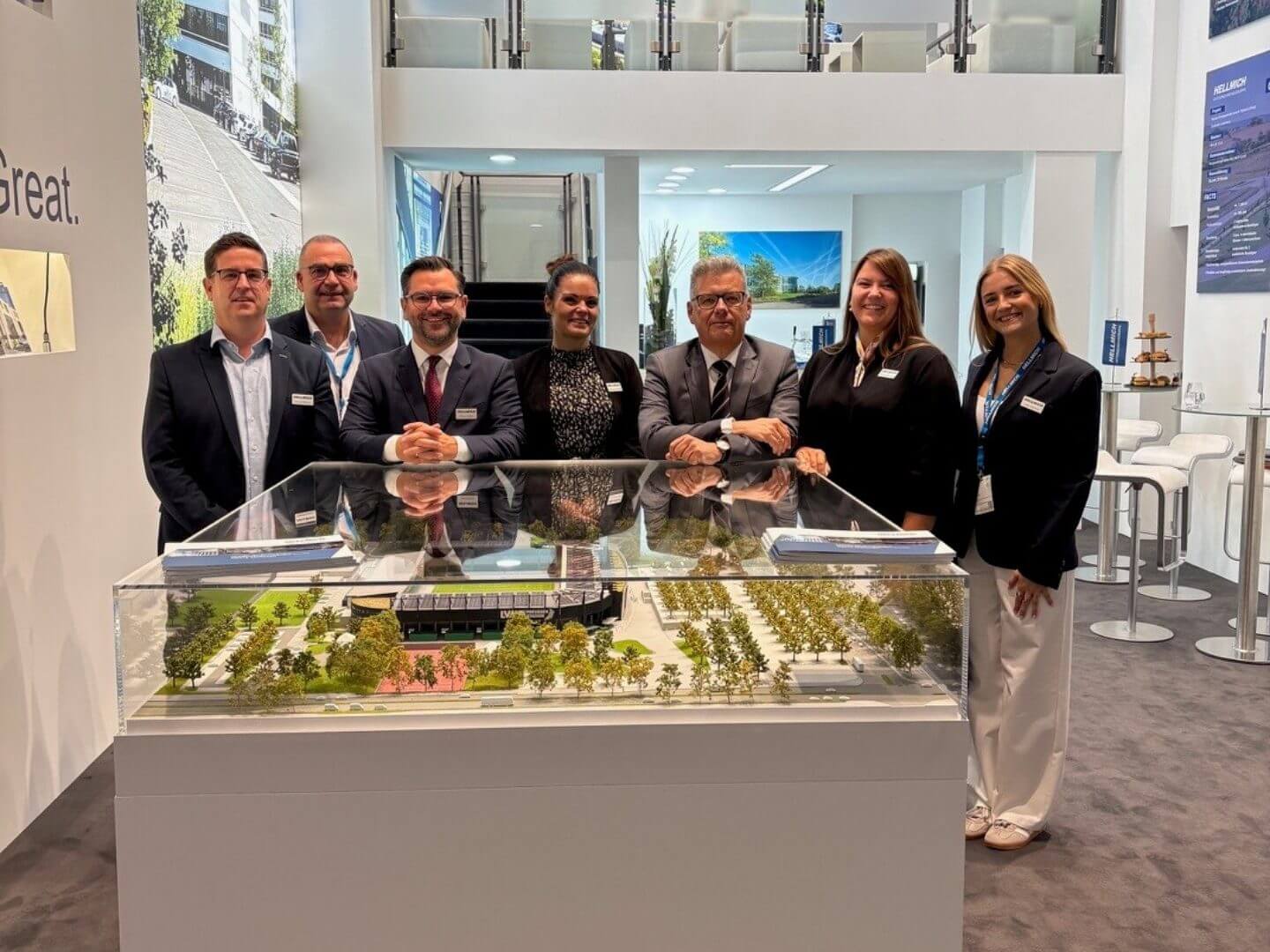 Mitarbeitergruppenfoto am Stand der Expo Real 2026 mit Architekturmodell im Vordergrund.
