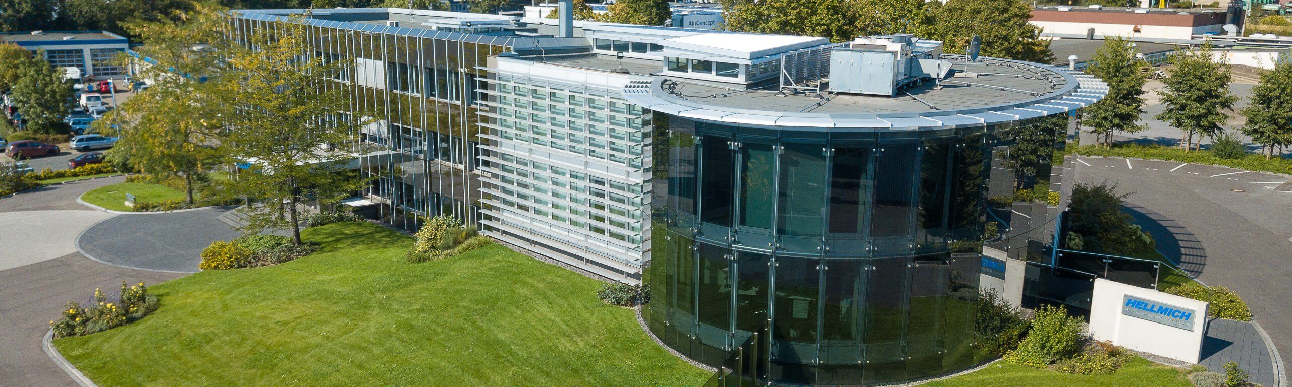 Moderne Firmenzentrale von HELLICH in Dinslaken mit Glas- und Metallfassade auf grünem Grundstück.