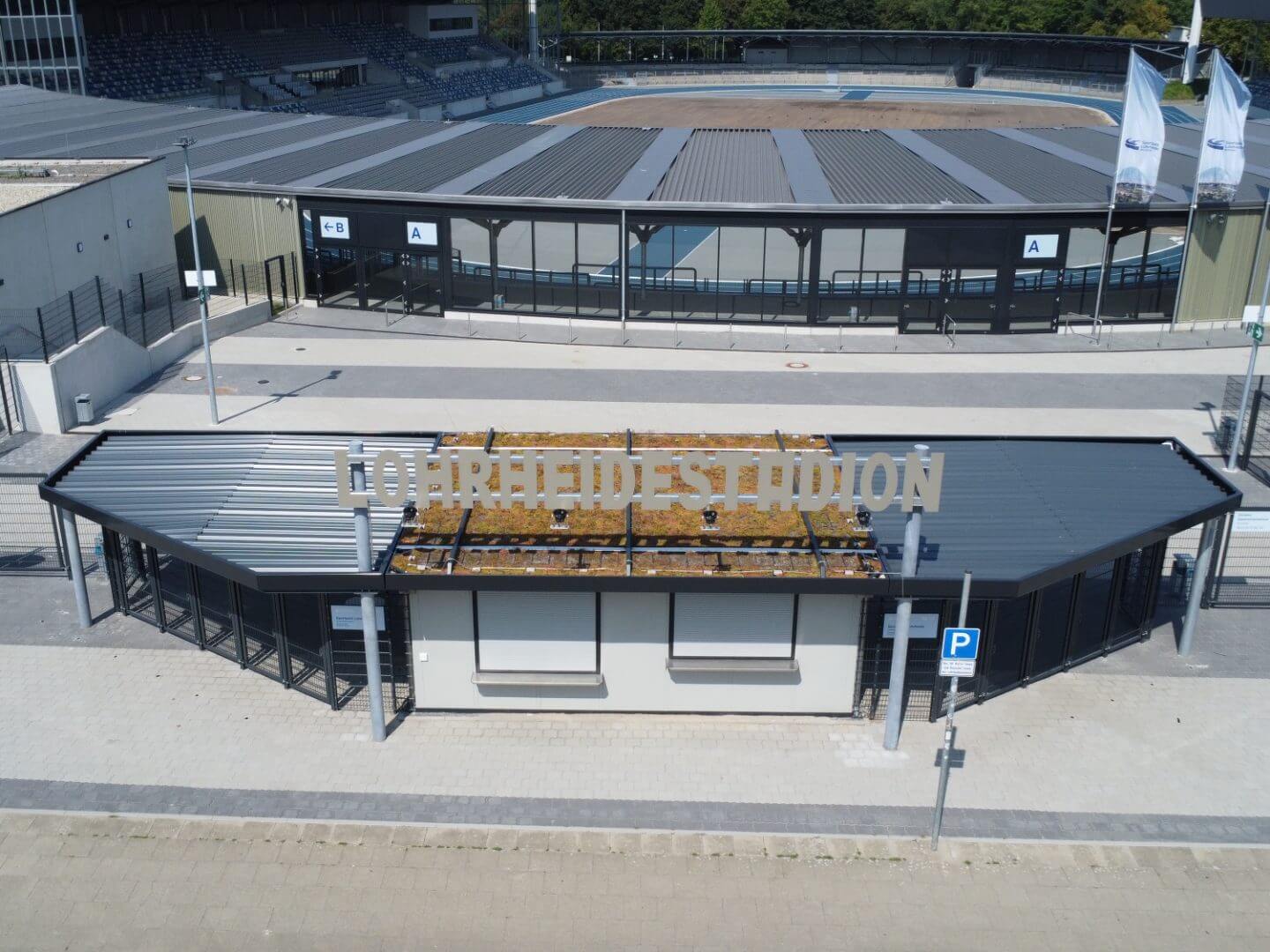 Das Lohrheidestadion in Bochum-Wattenscheid mit Eingangsbereich und Naturnah begrüntem Dach als erfolgreiches Bauprojekt der Hellmich Gruppe, präsentiert aus der Vogelperspektive.