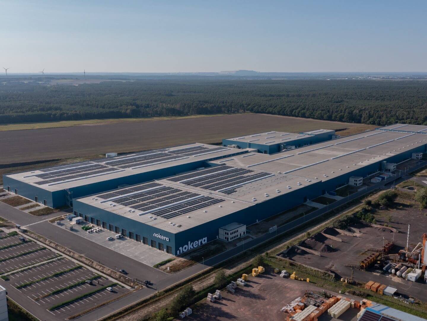 Luftaufnahme des Hellmich Bauprojekts Nokera Stegelitz mit großen Hallen und Solaranlagen auf dem Dach in ländlicher Umgebung. Luftaufnahme des Hellmich Bauprojekts Nokera Stegelitz mit großen Hallen und Solaranlagen auf dem Dach in ländlicher Umgebung.