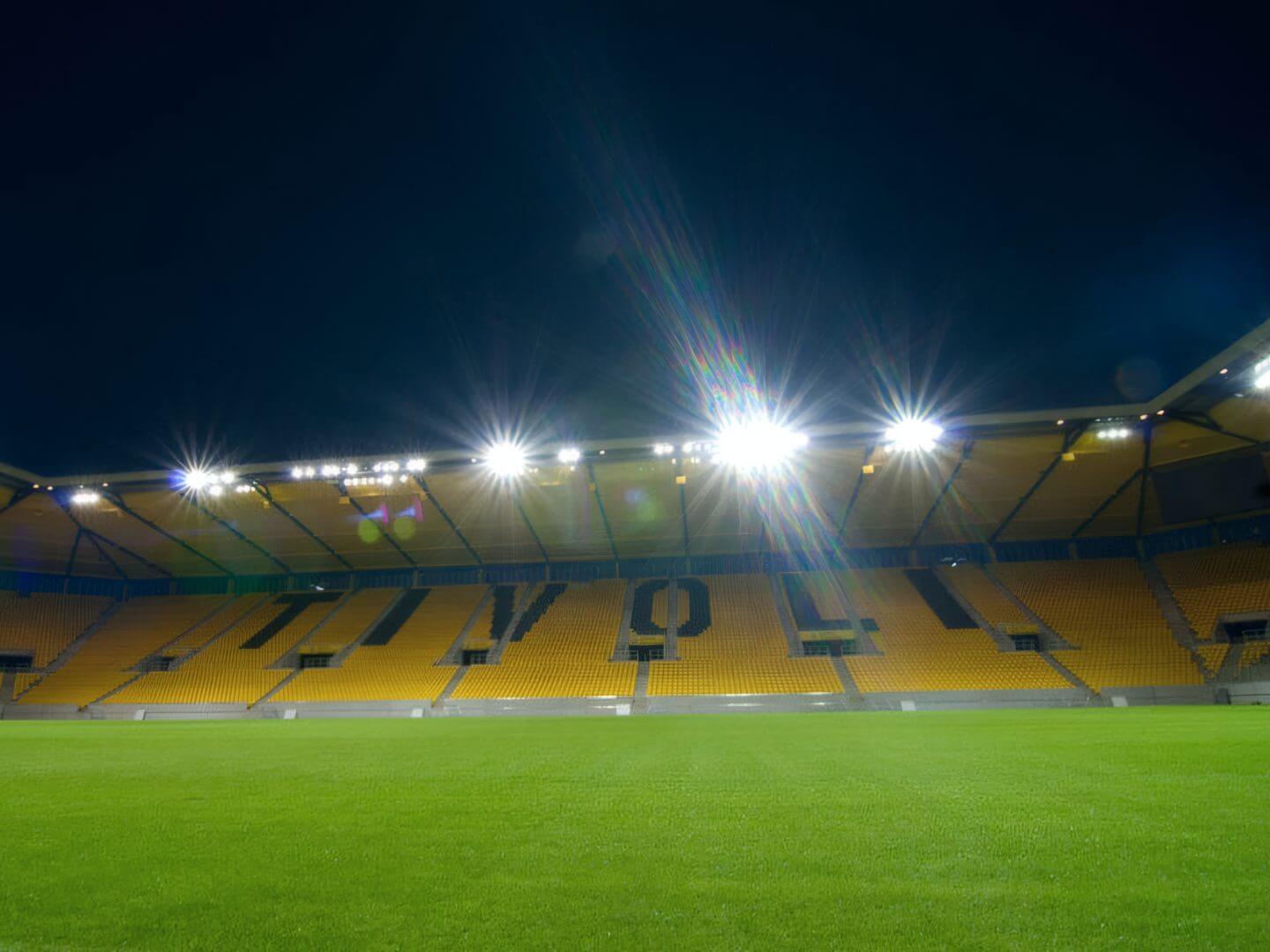 Nächtliche Ansicht des Tivoli Stadions in Aachen mit beleuchtetem Spielfeld und Tribünen als Referenzobjekt der Hellmich Gruppe im Bauwesen.