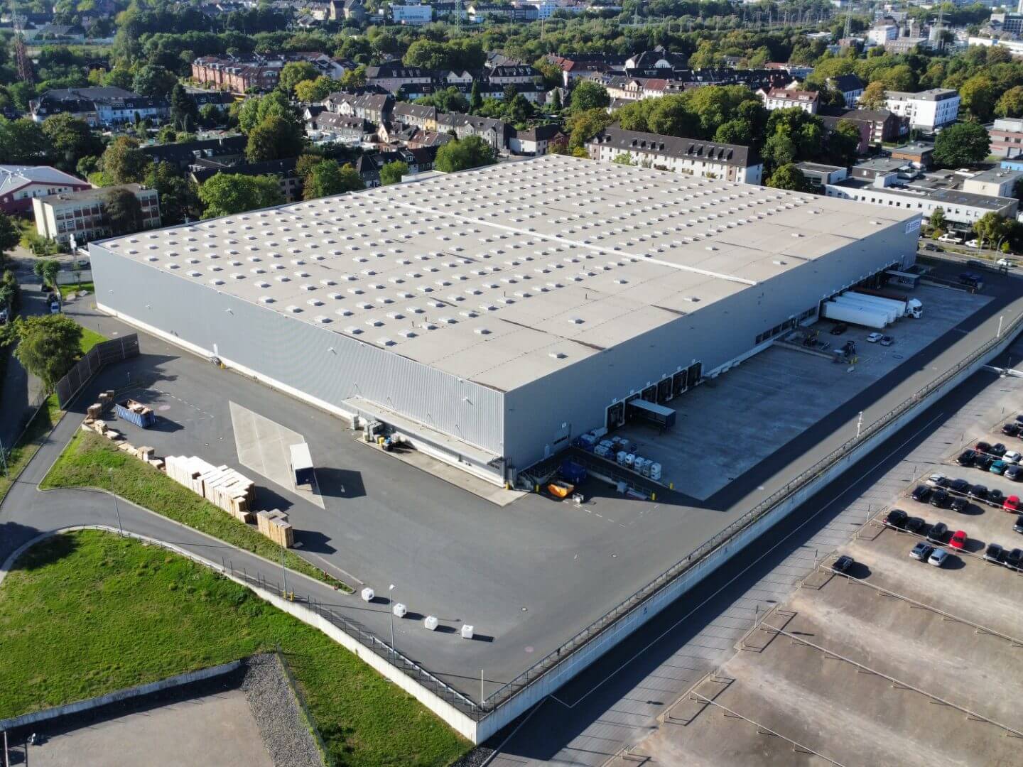 Luftaufnahme des fertiggestellten Gefahrstofflagers der Evonik, realisiert als Bauprojekt von Hellmich, mit einem großen, modernen Industriegebäude und umliegender Infrastruktur in städtischer Umgebung.
