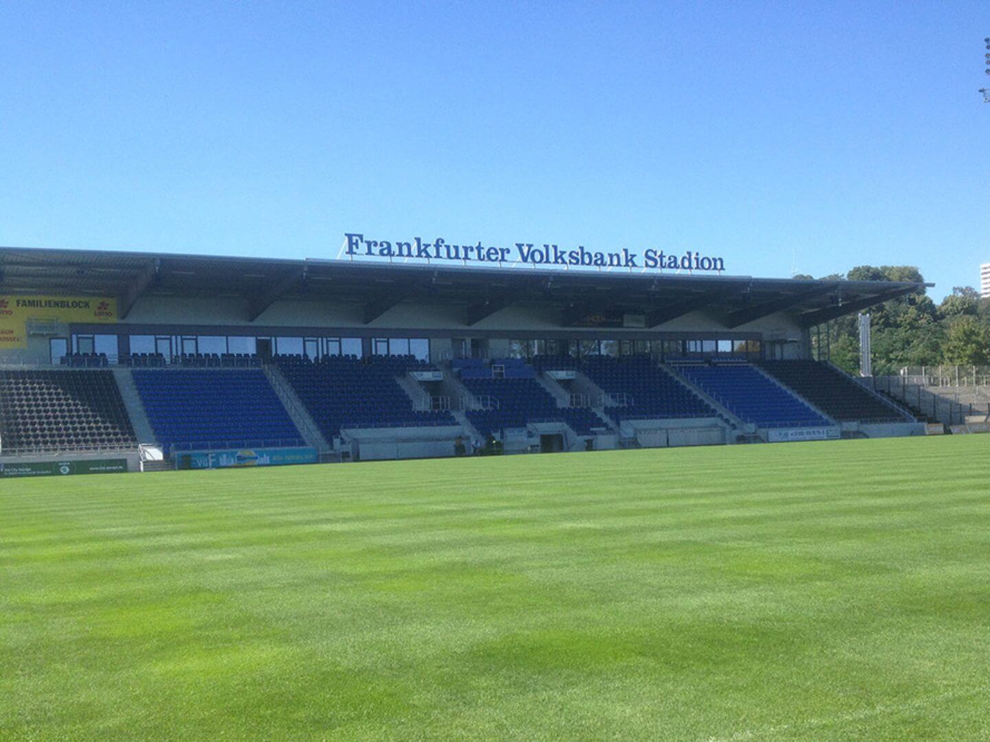 Das Frankfurter Volksbank Stadion, als bedeutendes Bauprojekt der Hellmich Gruppe, mit Blick auf die Haupttribüne und das Spielfeld unter klarem Himmel.