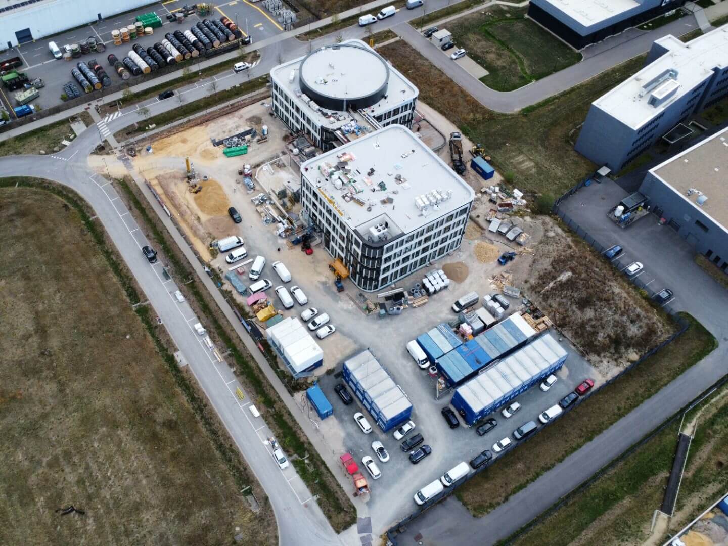 Luftaufnahme des Goodyear Bürogebäudes in Bissen, Luxemburg, im Bau durch die Hellmich Gruppe mit sichtbaren Baumaschinen und Fahrzeugen auf der Baustelle.