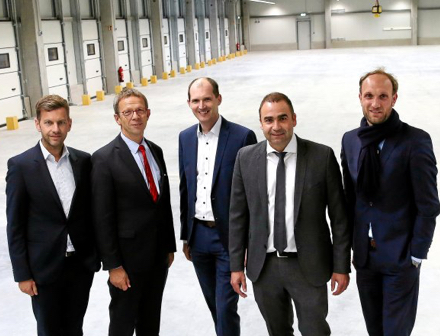 Fünf Männer stehen in einer großen, leeren Lagerhalle des neuen Zustellstützpunkts der Deutschen Post