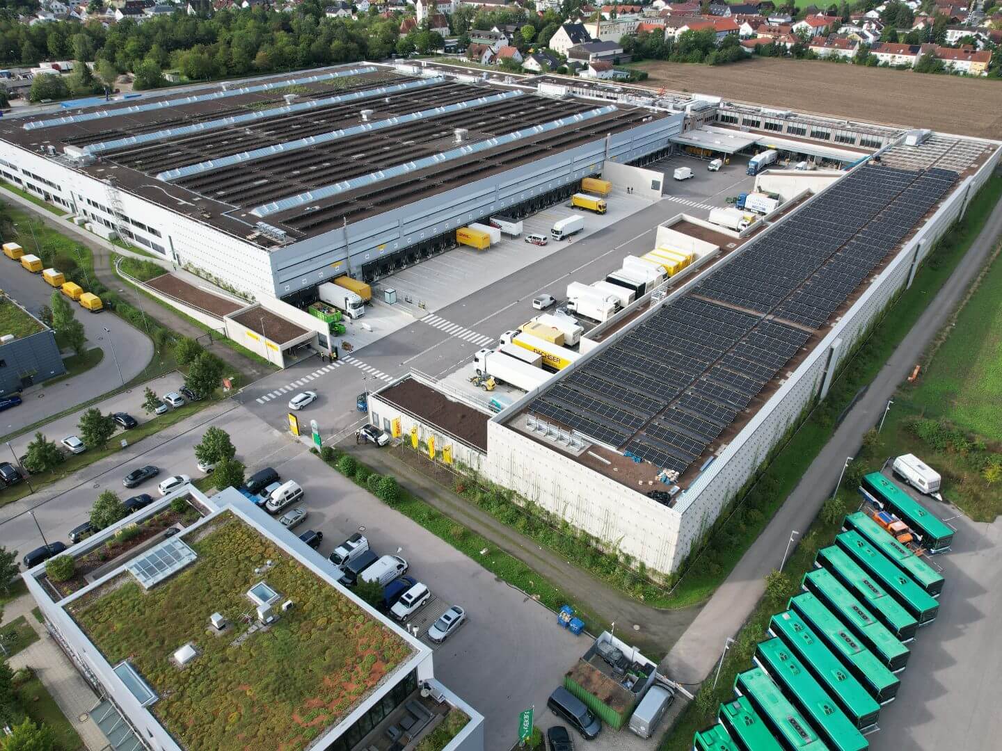 Luftaufnahme des DHL Briefzentrums in Germering, umgesetzt als Bauprojekt von Hellmich, mit mehreren Andockstellen und Lagerflächen für Zustellfahrzeuge. Luftaufnahme des DHL Briefzentrums in Germering, umgesetzt als Bauprojekt von Hellmich, mit mehreren Andockstellen und Lagerflächen für Zustellfahrzeuge.