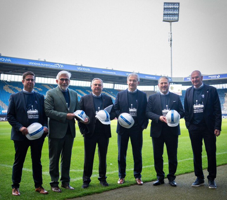 Vertreter stehen mit Helmen auf der Spielfläche des Ruhrstadions zur Sanierungseröffnung.