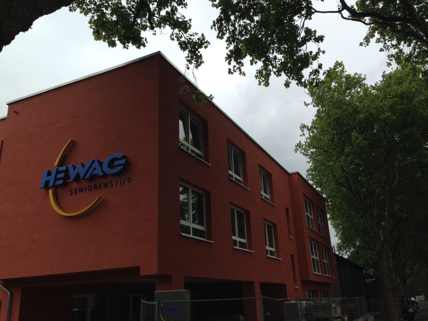 Außenansicht des HEWAG Seniorenstifts in Duisburg-Neumuehl, realisiert als Bauprojekt der Hellmich Gruppe, aufgenommen an einem bewölkten Tag mit umgebenden Bäumen.