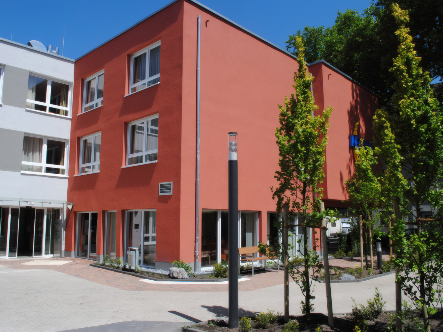Modernes Seniorenstift in Duisburg-Neumuehl mit rotem Fassadenanstrich und klarer Bauarchitektur, realisiert von der Hellmich Gruppe.