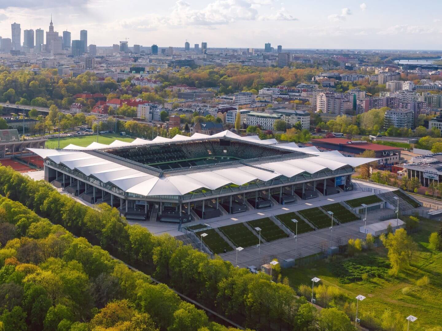 Das moderne Stadion Wojska Polskiego inmitten grüner Umgebung und urbaner Skyline.