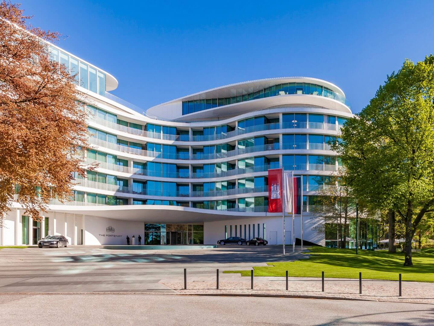Eingangsbereich und Front des The Fontenay Hotels in Hamburg mit Flaggen und gepflegtem Umfeld. Eingangsbereich und Front des The Fontenay Hotels in Hamburg mit Flaggen und gepflegtem Umfeld.
