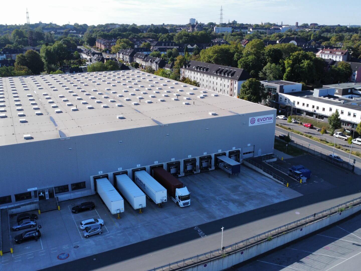 Luftaufnahme des Evonik Gefahrstofflagers als modernes Bauprojekt der Hellmich gruppe mit LKW-Verladeanlagen und städtischer Umgebung.