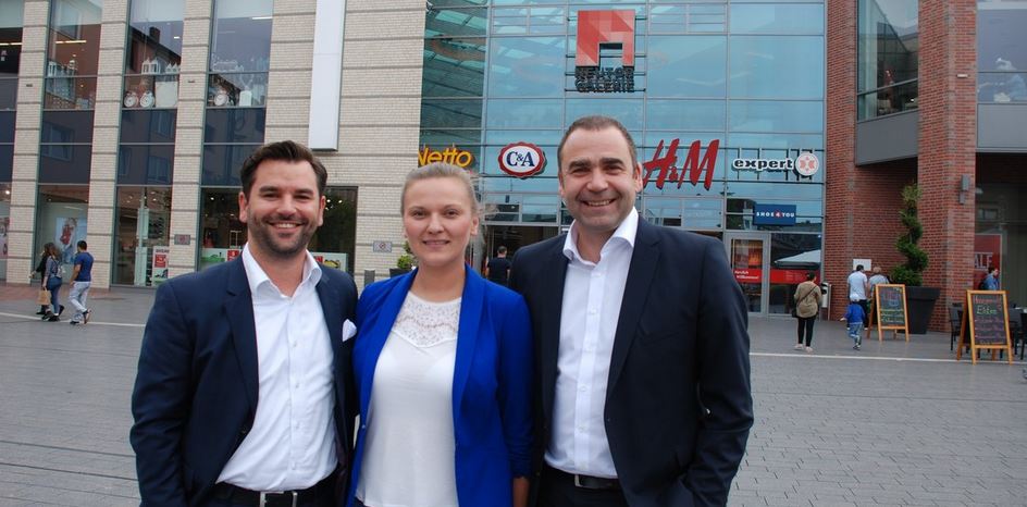 Neuer Bürgermeister gemeinsam mit zwei Personen vor dem Eingangsbereich der Neutor Galerie.