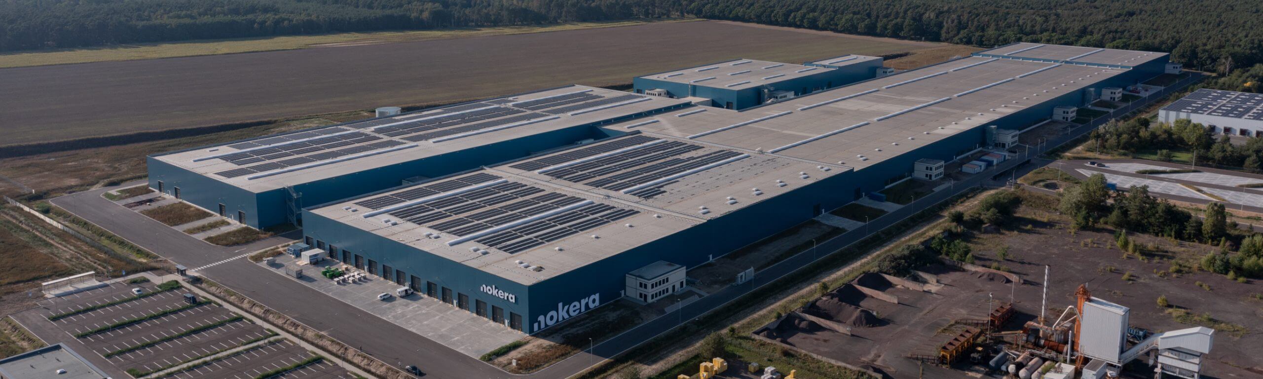Luftaufnahme des Nokera Stegelitz Bauprojekts, realisiert von Hellmich mit modernen Industriehallen und Solaranlagen auf dem Dach.