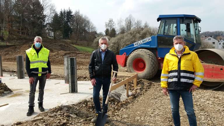 Drei Personen mit Schutzmasken besichtigen die Baustelle des neuen Zustellstützpunkts in Kierspe.