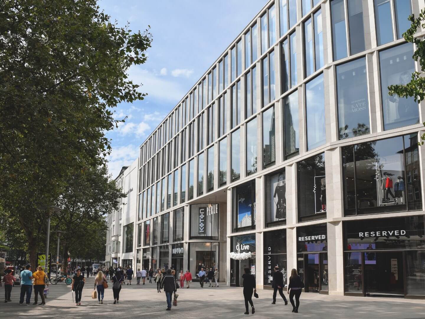 Modernes Büro- und Geschäftshaus an der Spitaler Straße in Hamburg, realisiert von der Hellmich Gruppe, mit großflächigen Glasfassaden und belebter Fußgängerzone.