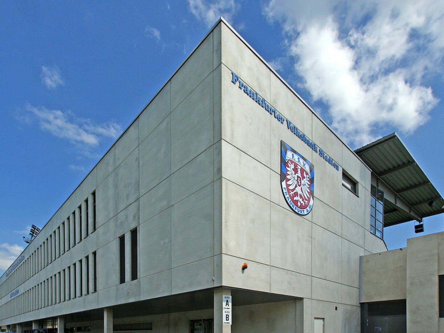Ansicht des Frankfurter Volksbank Stadions als erfolgreiches Bauprojekt der Hellmich Gruppe mit moderner Betonfassade und Vereinswappen.