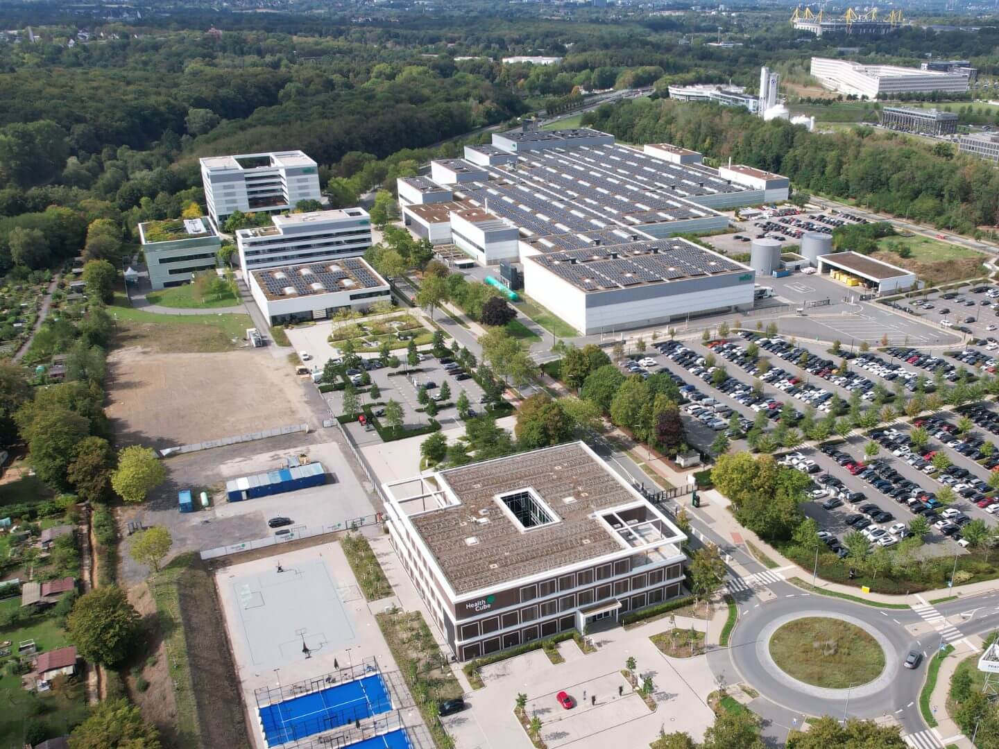 Luftaufnahme des Wilo Health Cube Gebäudes als zentrales Bauprojekt von Hellmich auf dem Firmen-Campus mit angrenzenden Parkflächen und weiteren Firmengebäuden. Luftaufnahme des Wilo Health Cube Gebäudes als zentrales Bauprojekt von Hellmich auf dem Firmen-Campus mit angrenzenden Parkflächen und weiteren Firmengebäuden.