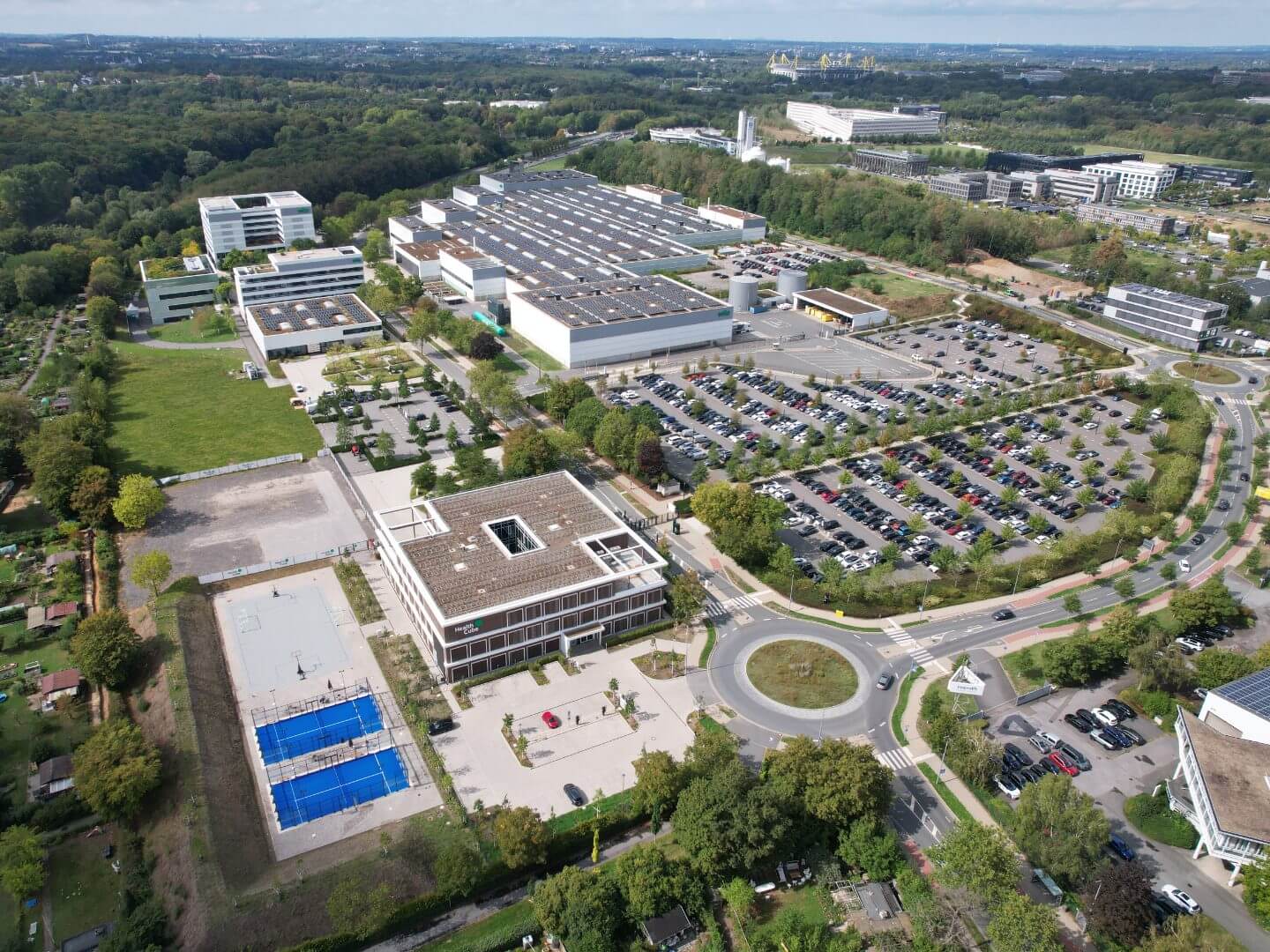 Luftaufnahme des Wilo Health Cube Gebäudes als zentrales Bauprojekt von Hellmich auf dem Firmen-Campus mit angrenzenden Parkflächen und weiteren Firmengebäuden. Luftaufnahme des Wilo Health Cube Gebäudes als zentrales Bauprojekt von Hellmich auf dem Firmen-Campus mit angrenzenden Parkflächen und weiteren Firmengebäuden.