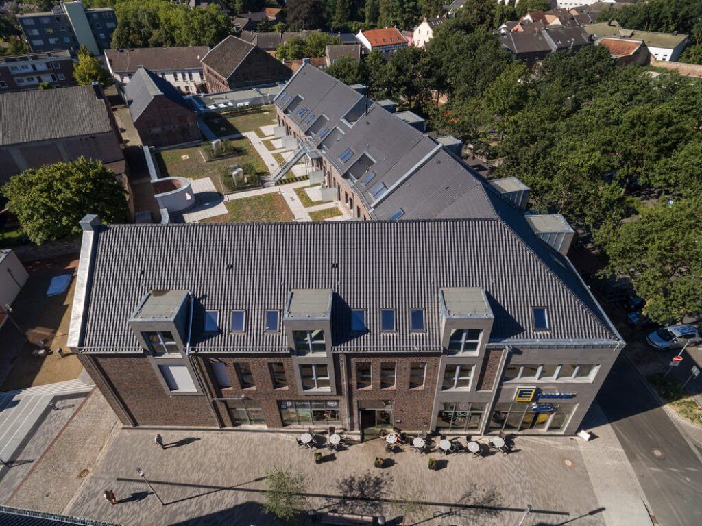 Luftaufnahme des modernen Wohn- und Geschäftshauses am Kesselsturm in Viersen-Dülken mit Außensitzplätzen.